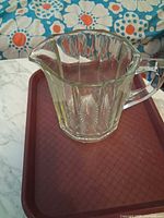 Side view of clear thick glass pitcher on tray