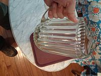 Side view of thick clear ribbed glass pitcher held by handle