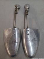 Front view of both aluminum shoe trees showing toe pieces and adjustment rods
