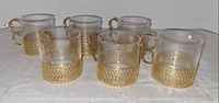 Front view of six glass cups with gold sleeves