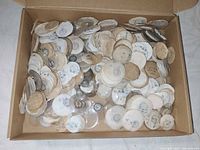 Box filled with numerous round glass watch crystals, many inside paper envelopes