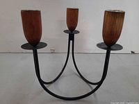 Front view showing three wood candle holders on black metal arms