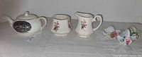 Full lot showing teapot, creamer, sugar, three baskets