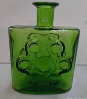 Front view of green glass decanter showing embossed circular motif