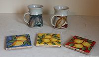 Two Robert Hopper mugs and three lemon tile coasters