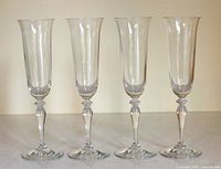 Four clear glass champagne flutes standing side by side