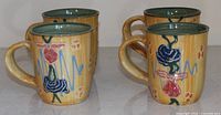 Front view of four matching hand-crafted ceramic mugs
