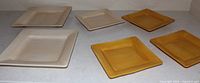 Six square plates laid out, showing two beige and four yellow