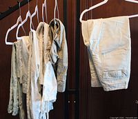 Front view of six pairs of pants hung on hangers