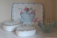 All items together: two CorningWare casseroles with lids, three glass bowls, decorative tray, vase