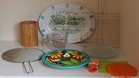 Overall lot with herb tray, Pyrex cups, glass plates, cooling racks, bamboo holder, splatter screen, floral plate, clips, trivets