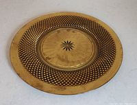 Front view showing gold finish, diamond pattern border, starburst center