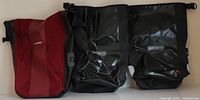 Front view of one red B'Twin pannier and two black Ortlieb panniers