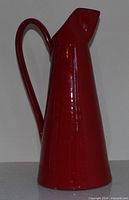 Full left profile of red ceramic pitcher showing handle and spout