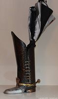Full view of boot-shaped hammered copper umbrella stand with umbrella inserted
