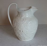 Front left view of white Wedgwood relief vase showing handle and grapevine pattern