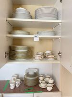 Cabinet shelves showing stacks of plates and cup-saucer sets