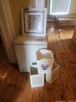 Full lot showing laundry hamper, framed mosaic mirror on top, three decorative boxes in front