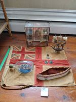 Overview of lot with flag, ship in bottle, wooden canoe, badges, display cabinet