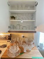 Cabinet shelves and countertop showing variety of glassware pieces