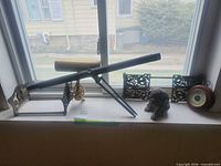 Window-sill view showing telescope on tripod, bookends, dog statue, barometer