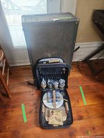 Suitcase standing upright behind opened picnic backpack showing overall lot