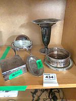 Group of five silver and silver plate pieces on shelf