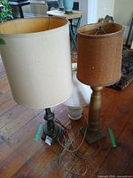 Two lamps standing: metal base with cream shade, wood base with brown shade; cords visible