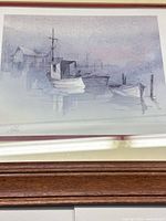 Close view of art print showing fishing boats scene, artist signature visible