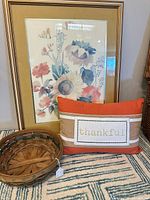 Framed floral print, woven basket and thankful pillow displayed together