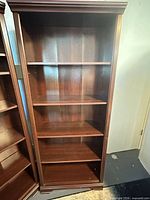 Full view of dark wood bookcase showing shelves and crown
