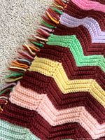 Close view of crocheted chevron afghan showing colour pattern and fringe