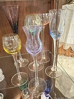 Front view of six assorted colored cordial glasses on shelf