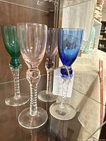 Front view of four twisted stem cordial glasses in different colors