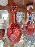 Front view of cranberry cut-to-clear cruet with stopper, grape pattern visible