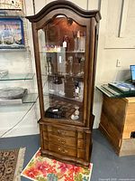 Front view of wood curio cabinet showing glass door, shelves, drawers