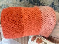 Rolled view of crocheted afghan showing orange and peach stripe sections and stitch detail