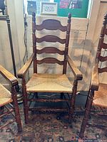 Front view of Hooker Furniture ladderback arm chair showing rush seat and turned legs