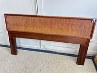 Front view of wooden headboard with cane panel