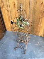 Front view of ornate metal wine rack with lattice body, leaf and grape accents, scroll feet