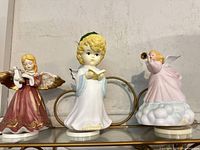 Front view of the three ceramic music box angel figurines on shelf