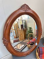 Full view of oval wood mirror showing carvings and glass