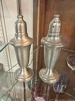 Two matching Empire pewter salt and pepper shakers on shelf