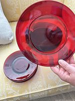 Stack of ruby red glass plates, one held to show color and style