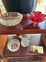 Four Waterford pieces on shelf: ashtray, red bowl, clear bowl, pitcher
