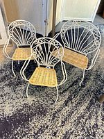 Three miniature white metal chairs with wicker seats on carpet