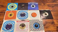 Group shot of ten 45 rpm records with assorted sleeves on tabletop