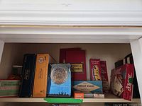 Shelf with multiple boxed games including Scrabble, Mystery Science Theater 3000, Snakes & Ladders, UNO, cribbage board, others