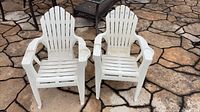 Pair of matching white plastic kids Adirondack chairs on patio