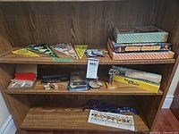 Shelf showing pennant flags, Chinese Chequers boxes, locomotive, vehicles, lanyards and cards